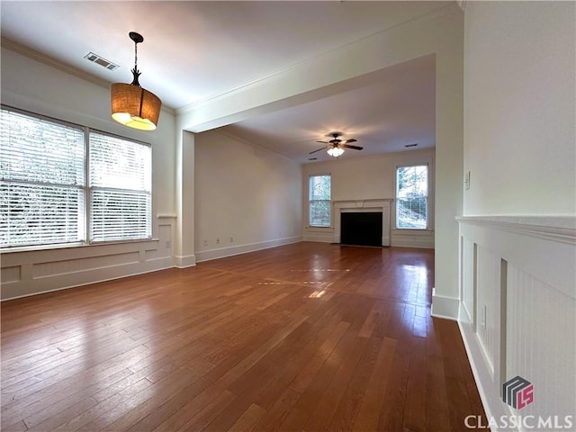 unfurnished living room featuring dark wood-style flooring, ornamental molding, visible vents, a ceiling fan, and a fireplace