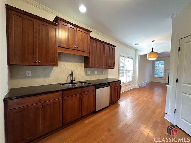 kitchen featuring crown molding, light wood finished floors, stainless steel dishwasher, a sink, and backsplash