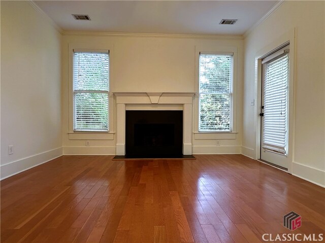 unfurnished living room featuring wood-type flooring, ornamental molding, and visible vents