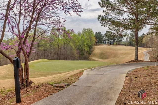 view of home's community with view of golf course and a yard