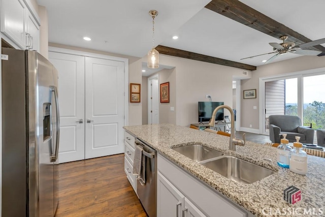 kitchen featuring beam ceiling, appliances with stainless steel finishes, a sink, open floor plan, and dark wood-style floors