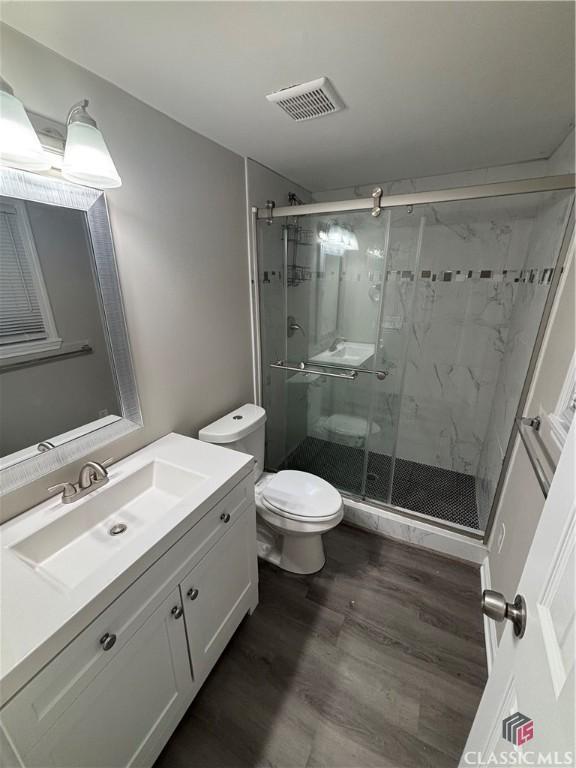 626 Vine St, Athens, GA 30601 - bathroom featuring visible vents, toilet, vanity, wood finished floors, and a stall shower