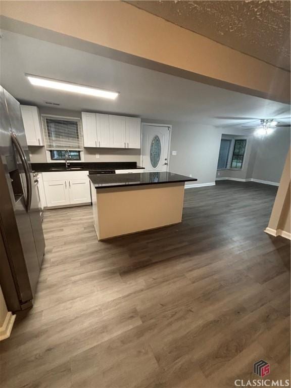 626 Vine St, Athens, GA 30601 - kitchen with stainless steel fridge with ice dispenser, a center island, a sink, dark countertops, and white cabinetry