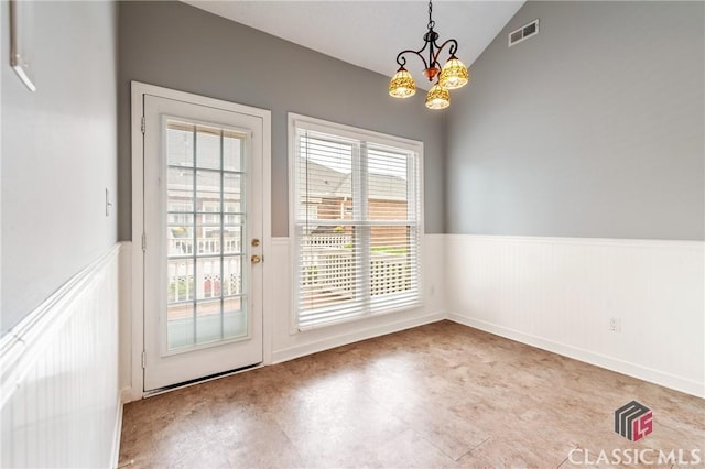 entryway with a notable chandelier, lofted ceiling, visible vents, and a wainscoted wall