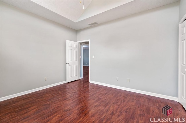 unfurnished room featuring visible vents, baseboards, vaulted ceiling, and wood finished floors