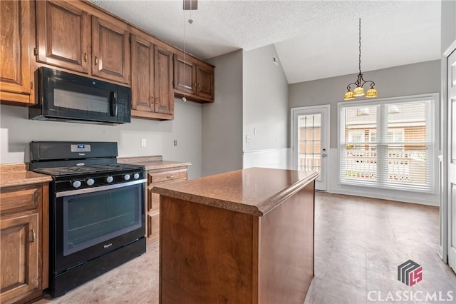 kitchen featuring decorative light fixtures, brown cabinets, vaulted ceiling, and black appliances
