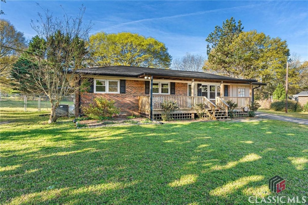 ranch-style house featuring a porch, brick siding, fence, and a front lawn
