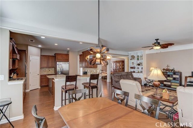 6706 Mill Rock Ct, Hoschton, GA 30548 - kitchen with a peninsula, premium range hood, ornate columns, a kitchen bar, and stainless steel appliances