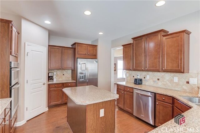 6706 Mill Rock Ct, Hoschton, GA 30548 - kitchen with visible vents, wood finished floors, stainless steel appliances, premium range hood, and decorative backsplash