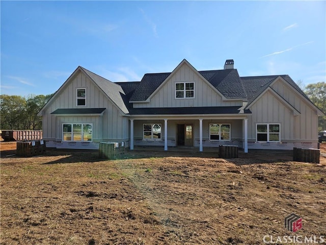 view of front of home featuring roof with shingles, board and batten siding, and a chimney