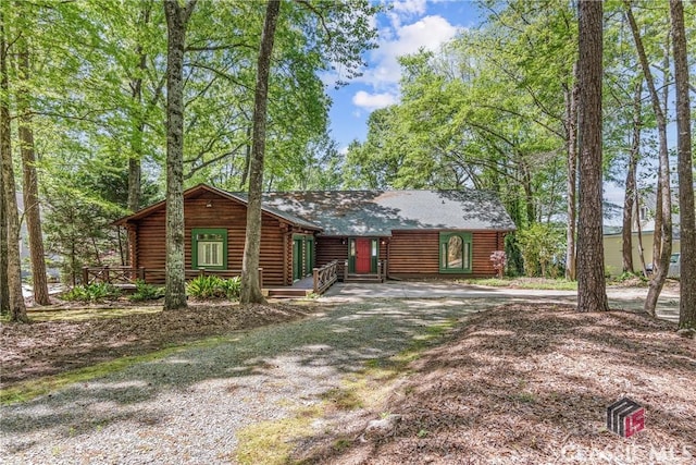 view of front of property featuring driveway, log exterior, and a shingled roof