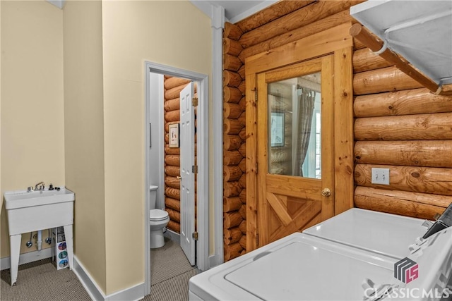laundry room with washing machine and dryer, baseboards, rustic walls, and laundry area