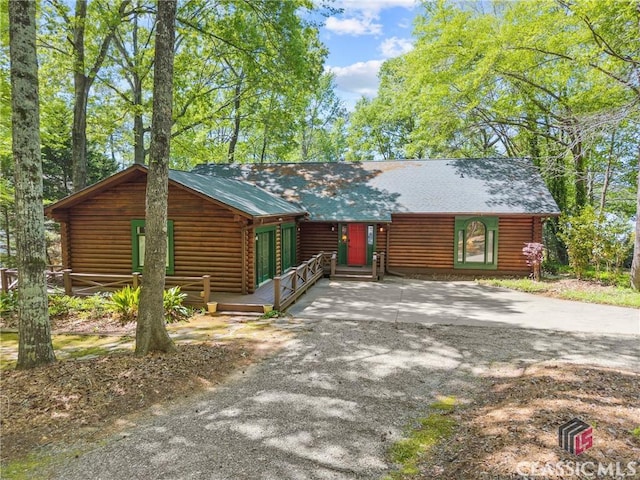 rustic home with log siding and driveway