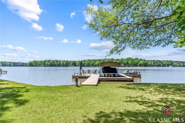 view of dock with a water view, a view of trees, a yard, and boat lift