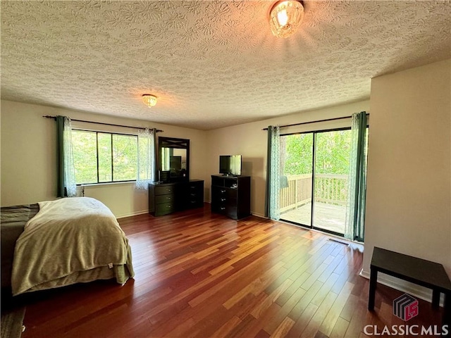 bedroom featuring dark wood-style flooring, multiple windows, access to exterior, and a textured ceiling