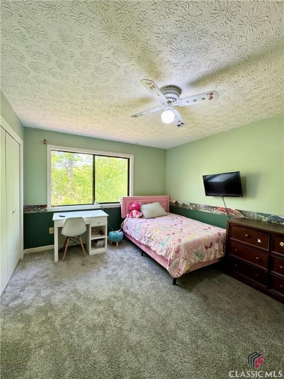 bedroom with a closet, carpet floors, a textured ceiling, and a ceiling fan