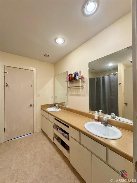 full bathroom featuring recessed lighting, double vanity, and a sink
