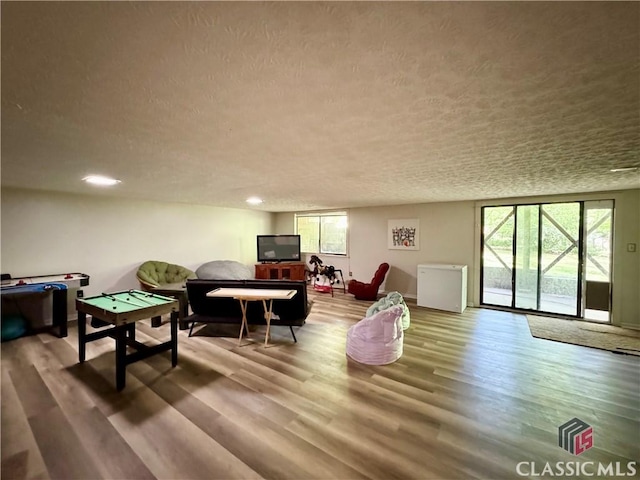 recreation room with recessed lighting, wood finished floors, and a textured ceiling