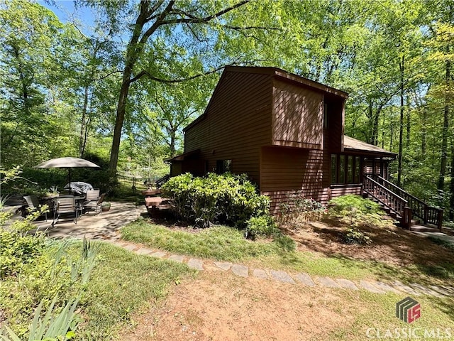 view of side of home featuring stairway and a patio area