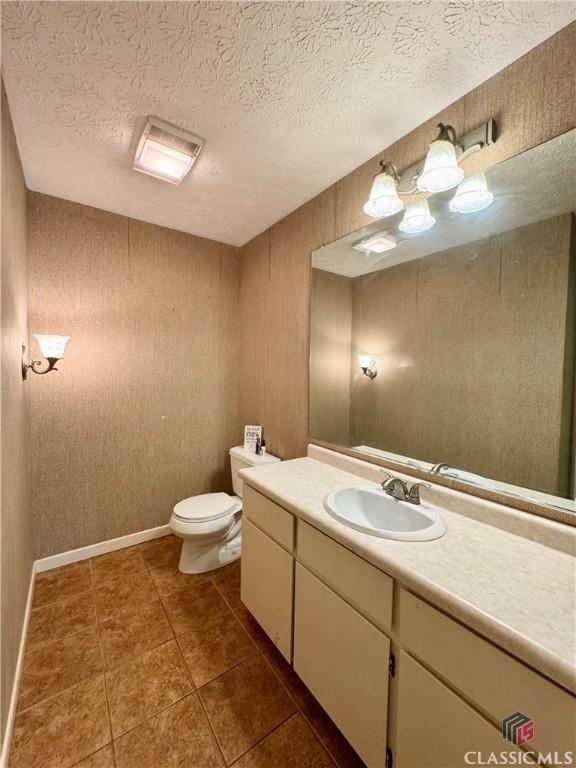 bathroom with a textured ceiling, toilet, vanity, and tile patterned floors