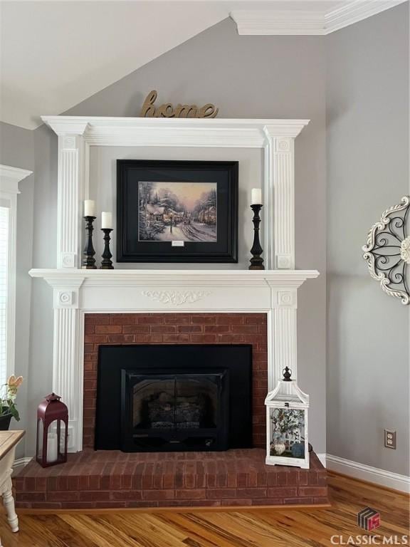 details featuring wood finished floors, a brick fireplace, baseboards, and ornamental molding