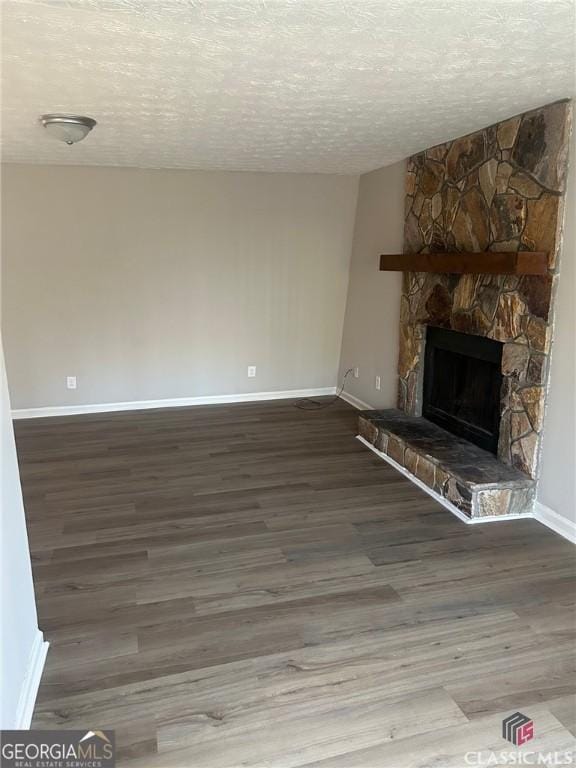 435 Rustwood Dr, Athens, GA 30606 - unfurnished living room featuring baseboards, wood finished floors, a stone fireplace, and a textured ceiling