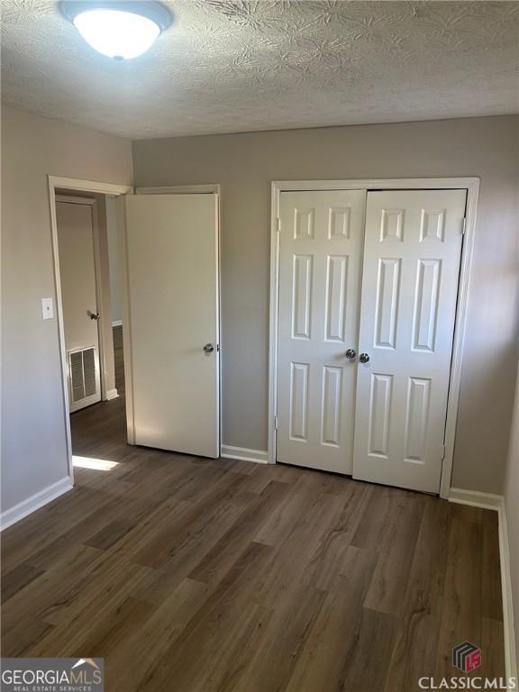 435 Rustwood Dr, Athens, GA 30606 - unfurnished bedroom featuring dark wood-type flooring, visible vents, and baseboards