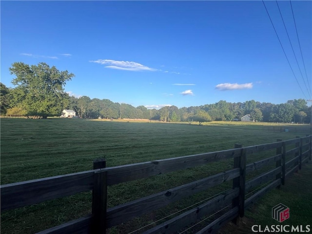 view of yard with fence and a rural view