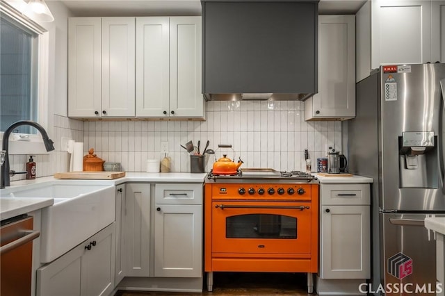 kitchen with backsplash, stainless steel appliances, light countertops, and wall chimney range hood