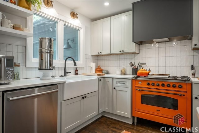 kitchen featuring dark wood finished floors, stainless steel appliances, extractor fan, backsplash, and a sink