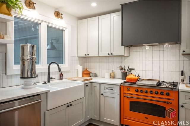kitchen with tasteful backsplash, stainless steel appliances, light countertops, and a sink