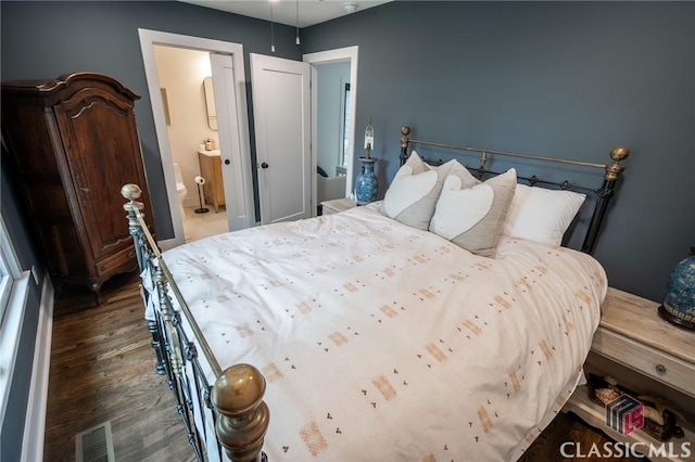 bedroom featuring visible vents, wood finished floors, and ensuite bathroom