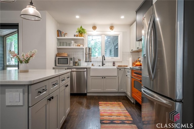 kitchen featuring decorative backsplash, appliances with stainless steel finishes, light countertops, a sink, and dark wood-style floors
