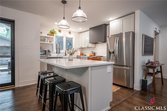 kitchen with wall chimney range hood, dark wood-type flooring, stainless steel appliances, and backsplash