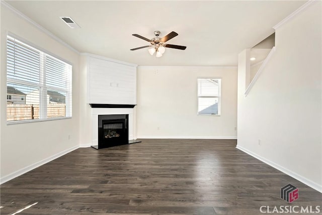 unfurnished living room featuring crown molding, a fireplace with raised hearth, ceiling fan, dark wood-type flooring, and visible vents