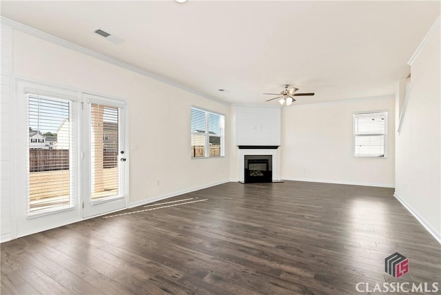 unfurnished living room featuring dark wood-style flooring, a wealth of natural light, crown molding, and ceiling fan
