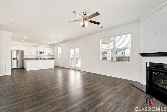 unfurnished living room featuring recessed lighting, ornamental molding, dark wood-style flooring, a glass covered fireplace, and ceiling fan