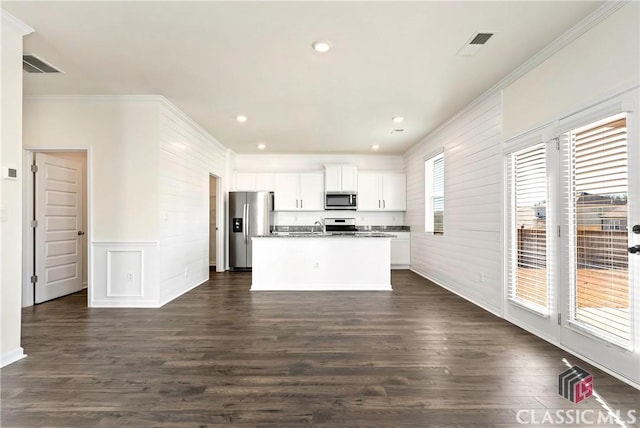 kitchen with an island with sink, appliances with stainless steel finishes, crown molding, and white cabinetry