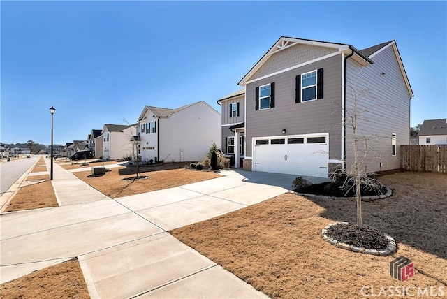 view of front of house featuring fence, concrete driveway, a residential view, and a garage
