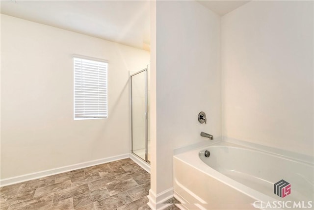 bathroom featuring a shower stall, baseboards, and a bath