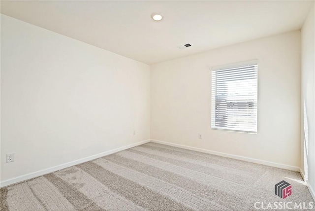 spare room featuring baseboards, visible vents, and light carpet