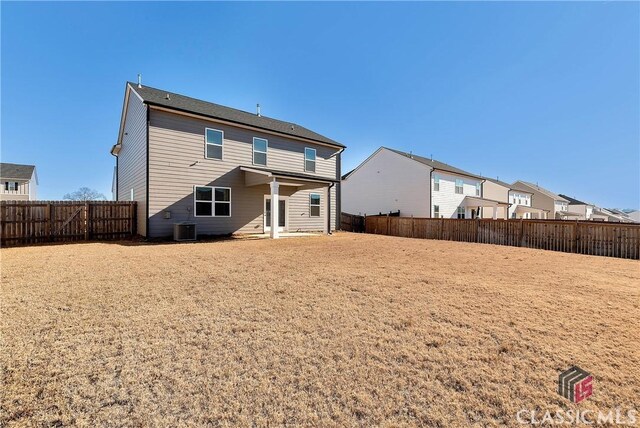 back of property with central AC and a fenced backyard