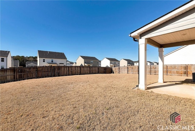 view of yard featuring a fenced backyard, a residential view, and a patio