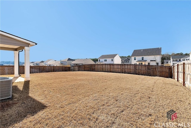 view of yard with a fenced backyard, central air condition unit, and a residential view
