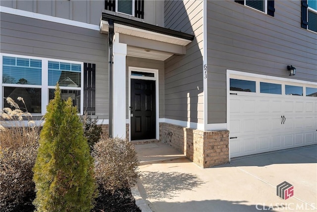 doorway to property with board and batten siding, stone siding, and a garage