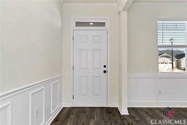 doorway featuring dark wood finished floors, a decorative wall, crown molding, and a wainscoted wall