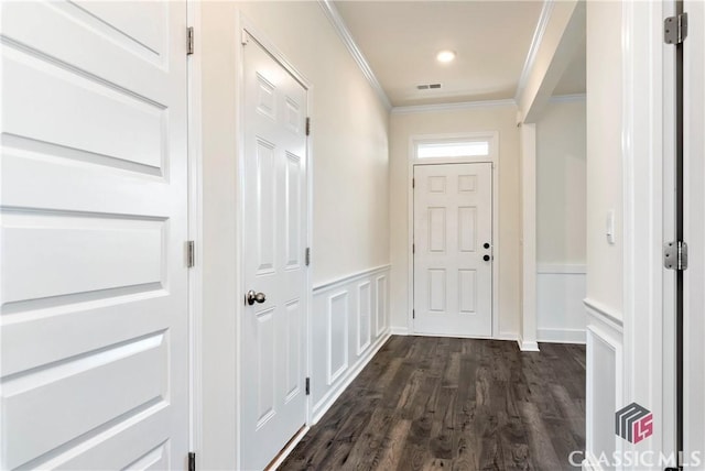 doorway to outside featuring dark wood-style floors, a decorative wall, a wainscoted wall, ornamental molding, and visible vents