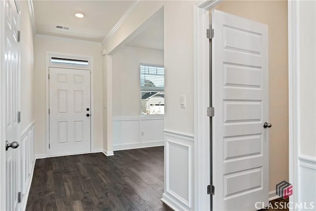 foyer entrance featuring a wainscoted wall, dark wood-style flooring, visible vents, a decorative wall, and ornamental molding