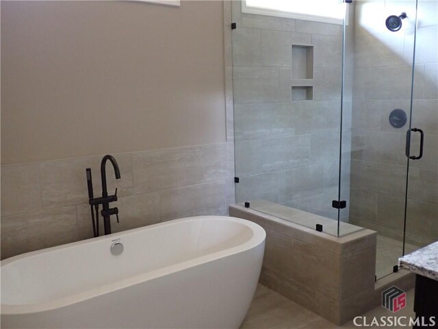 41 Hometown Ct, Jefferson, GA 30549 - bathroom with a shower stall, a soaking tub, and tile walls