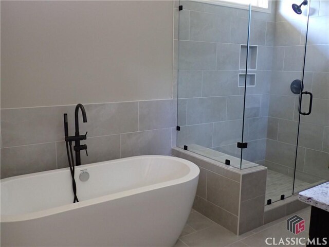 37 Hometown Ct, Jefferson, GA 30549 - bathroom featuring a freestanding bath, tile walls, tile patterned floors, and a stall shower